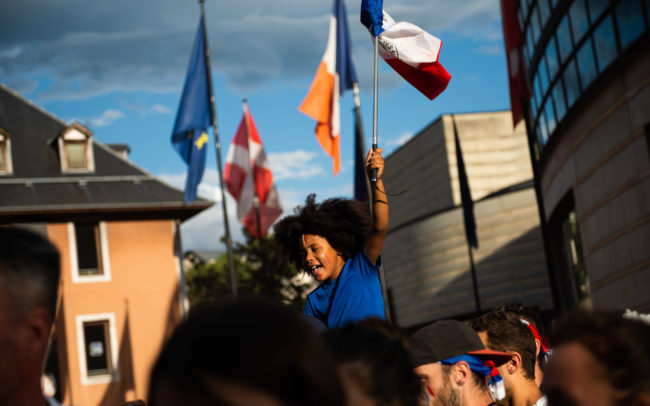 Un enfant est porté par son père avec un drapeau français.