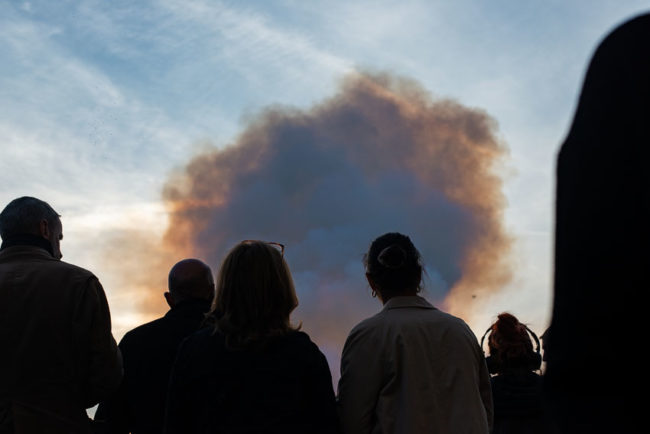 The crowd watches the cloud of smoke from the fire of Notre-Dame de Paris. La foule regarde le nuage de fumée de l’incendie de Notre-Dame de Paris.